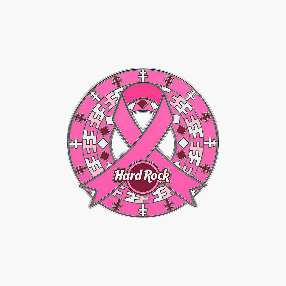 Graphic emblem pin featuring a prominent pink awareness ribbon wrapped around a circular design. The center contains the text "Hard Rock" on a maroon circle, surrounded by geometric patterns in pink, white, and maroon. The design appears on a clean white background, emphasizing the ribbon and central text. Overall, the image conveys a supportive, cause-related theme with bold, contrasting colors.